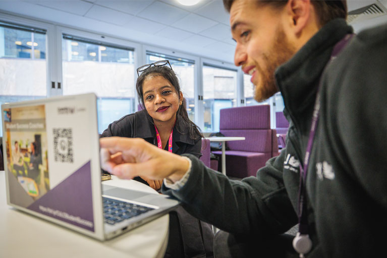 Success coach and student using a laptop