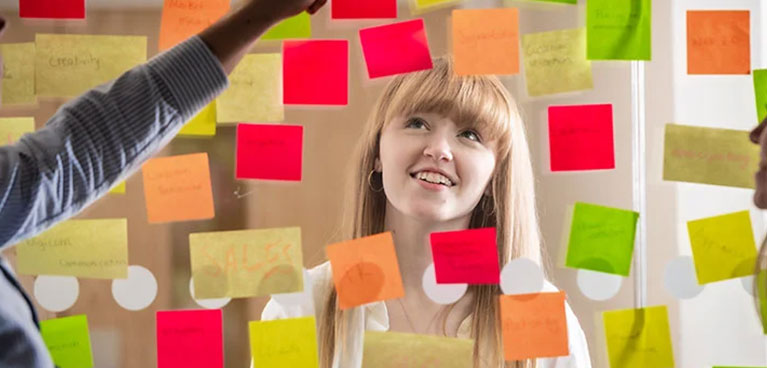 Girl looking at post it notes on a  clear board