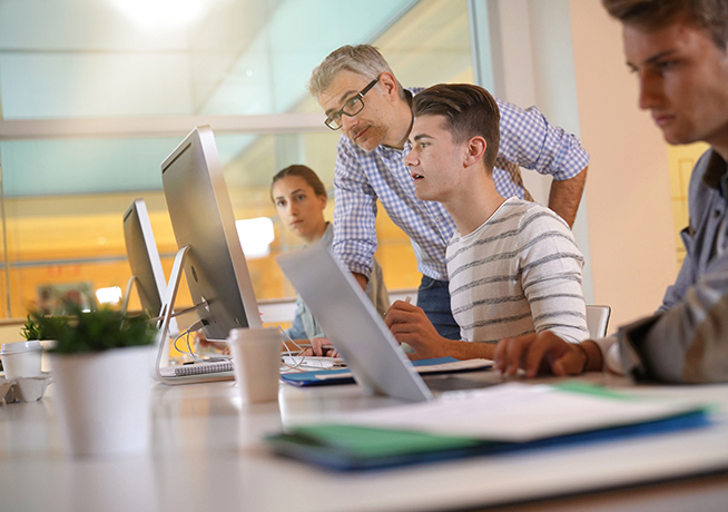 Teacher helping students in a computer studio