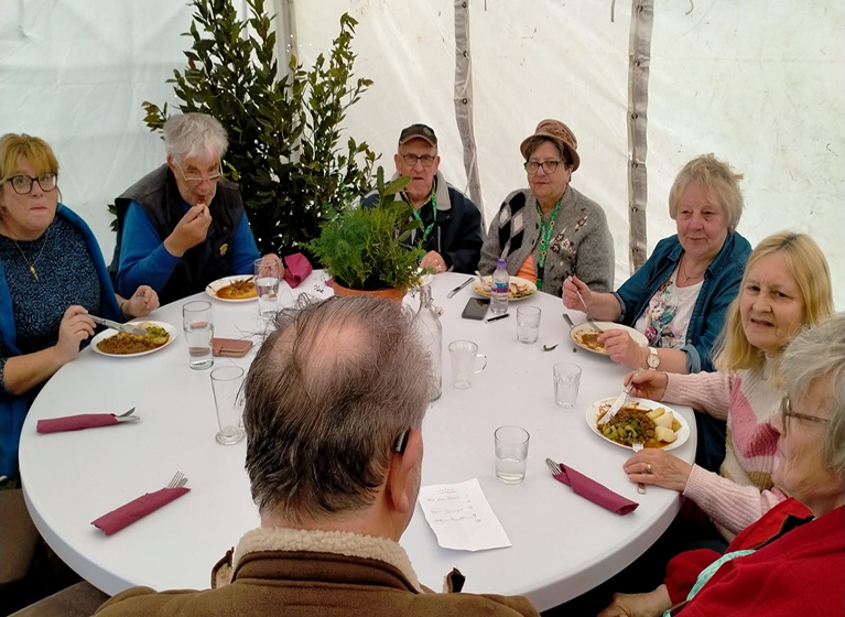 Elderly people sat around a table eating Christmas dinner