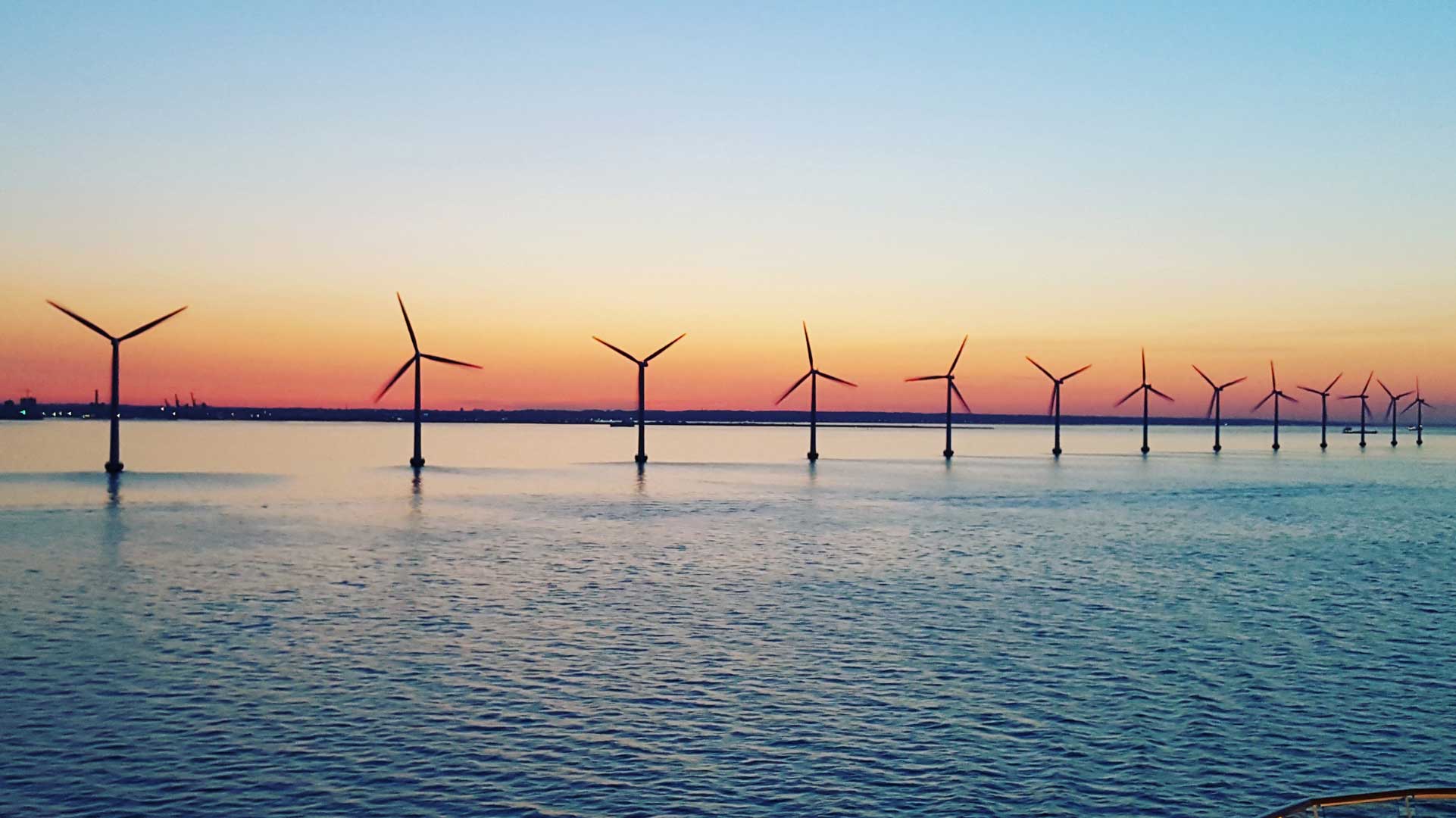 Wind turbines in the sea at sunset.