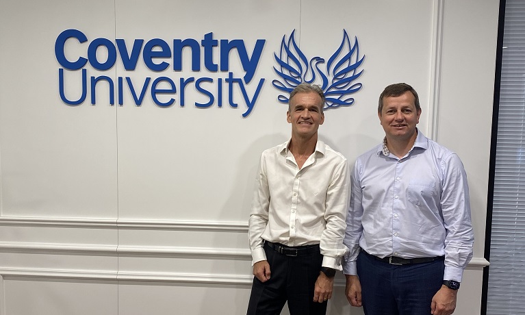 Two men standing next to a Coventry University sign