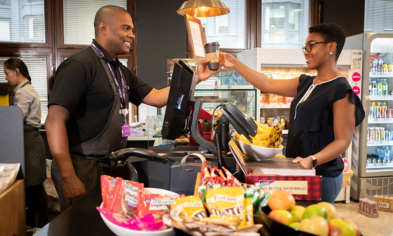 Coffee shop staff member passing coffee to a student in the University House cafe