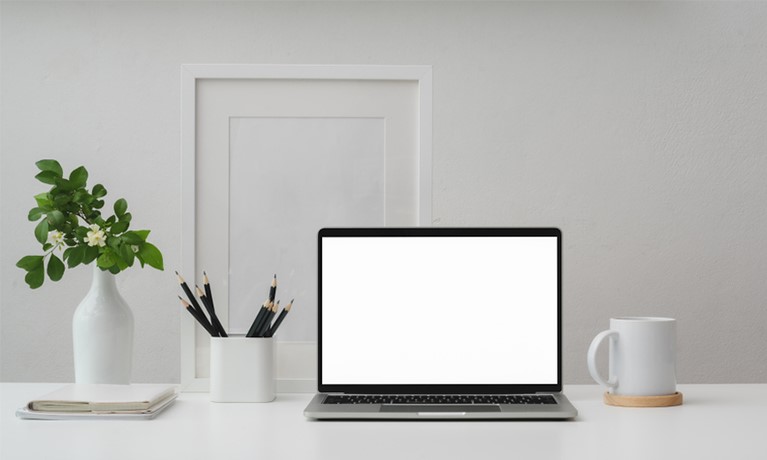 desk with laptop pens plant and mug