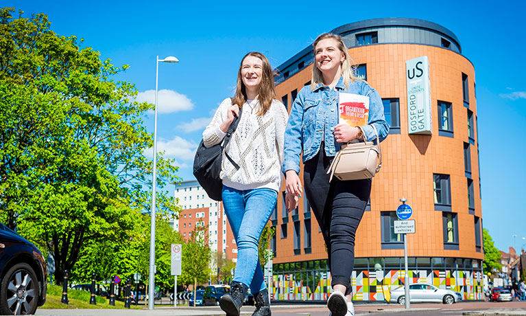 Two students walking outside Gosford Gate accommodation.