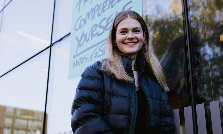 Smiling student standing in front of university building