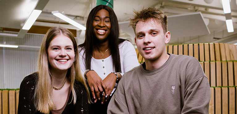 Head and shoulder image of three students smiling at the camera