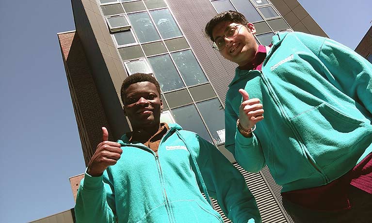 Two students in green fleece tops standing outside accommodation 