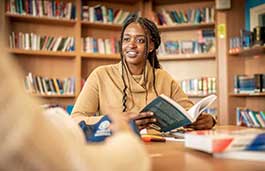 Female wearing a beige top is reading in a library