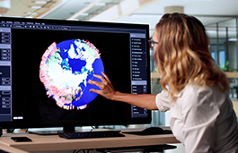 A woman pointing at a data graph on a computer screen