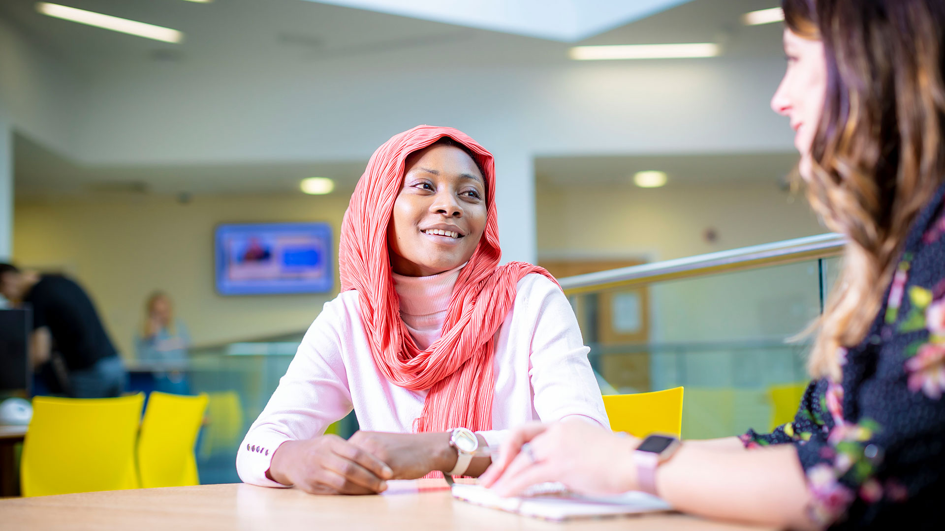 Two women sat at a table smiling at each other