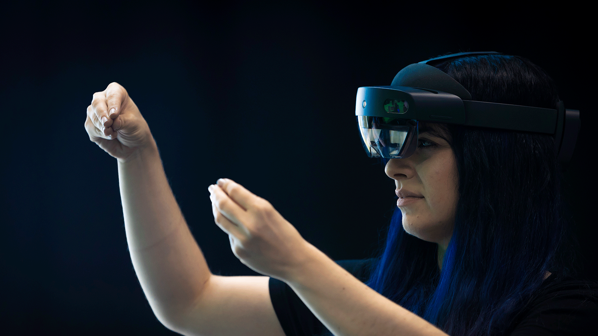 Young woman wearing a VR headset playing against a green screen