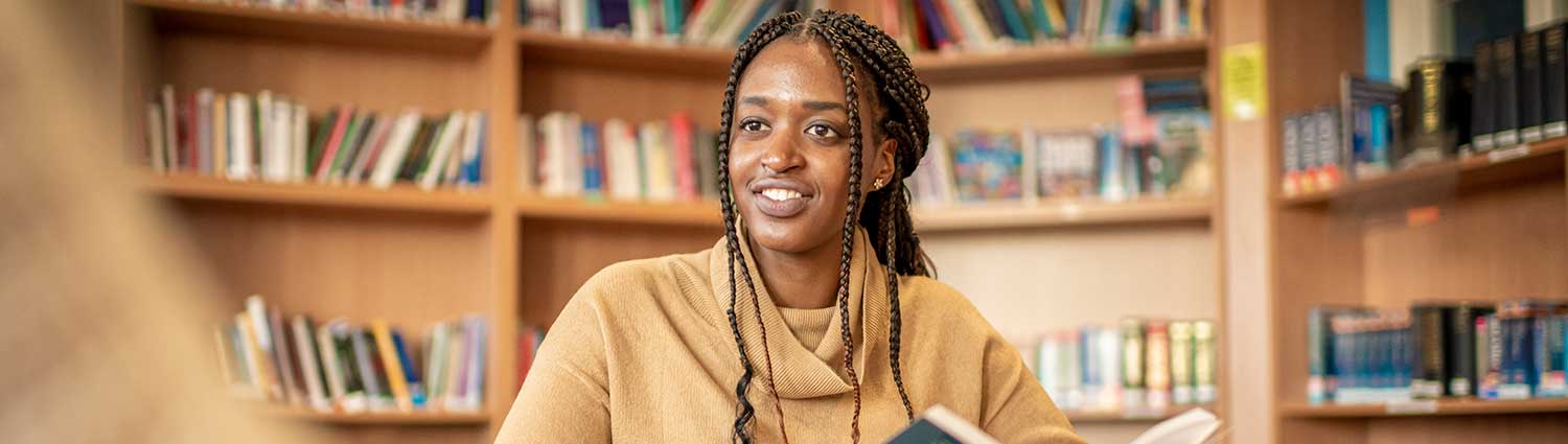 Female wearing a beige top is reading in a library