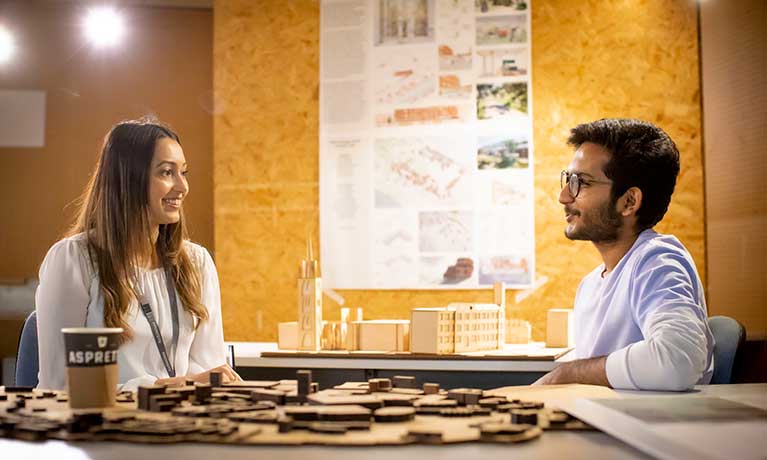 Two students sat at a table with wooden models pieces