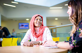 Two women sat at a table smiling at each other