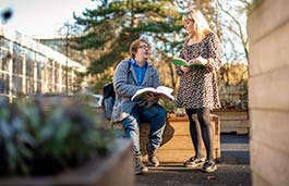 students in uni grounds reading books and chatting 