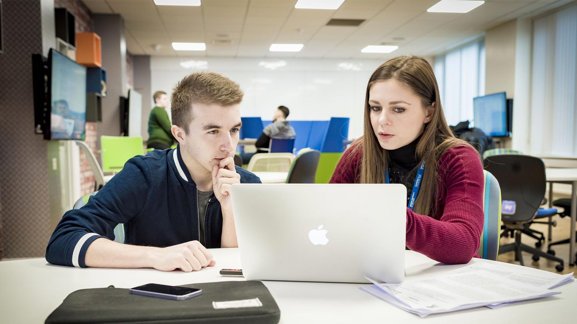 A student and tutor in the DigiComm Lab working on a macbook