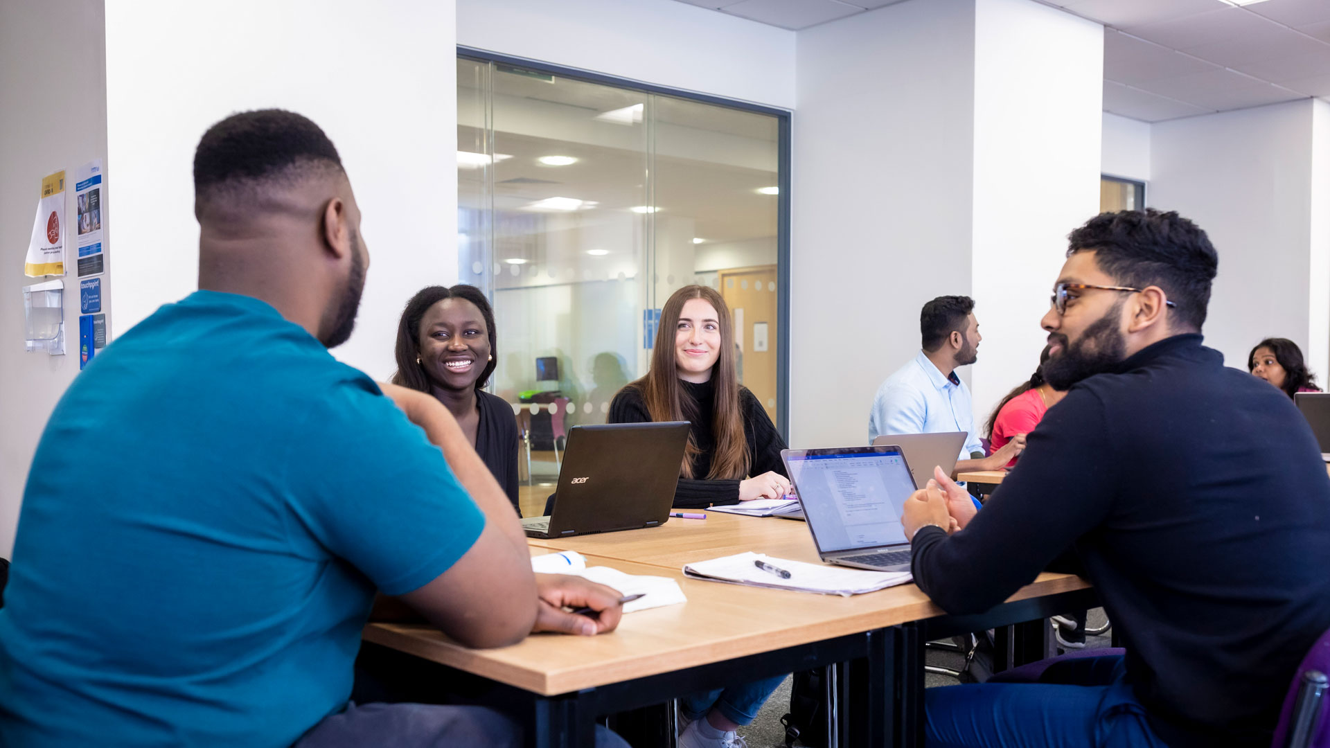 group of students around a table smiling and chatting 