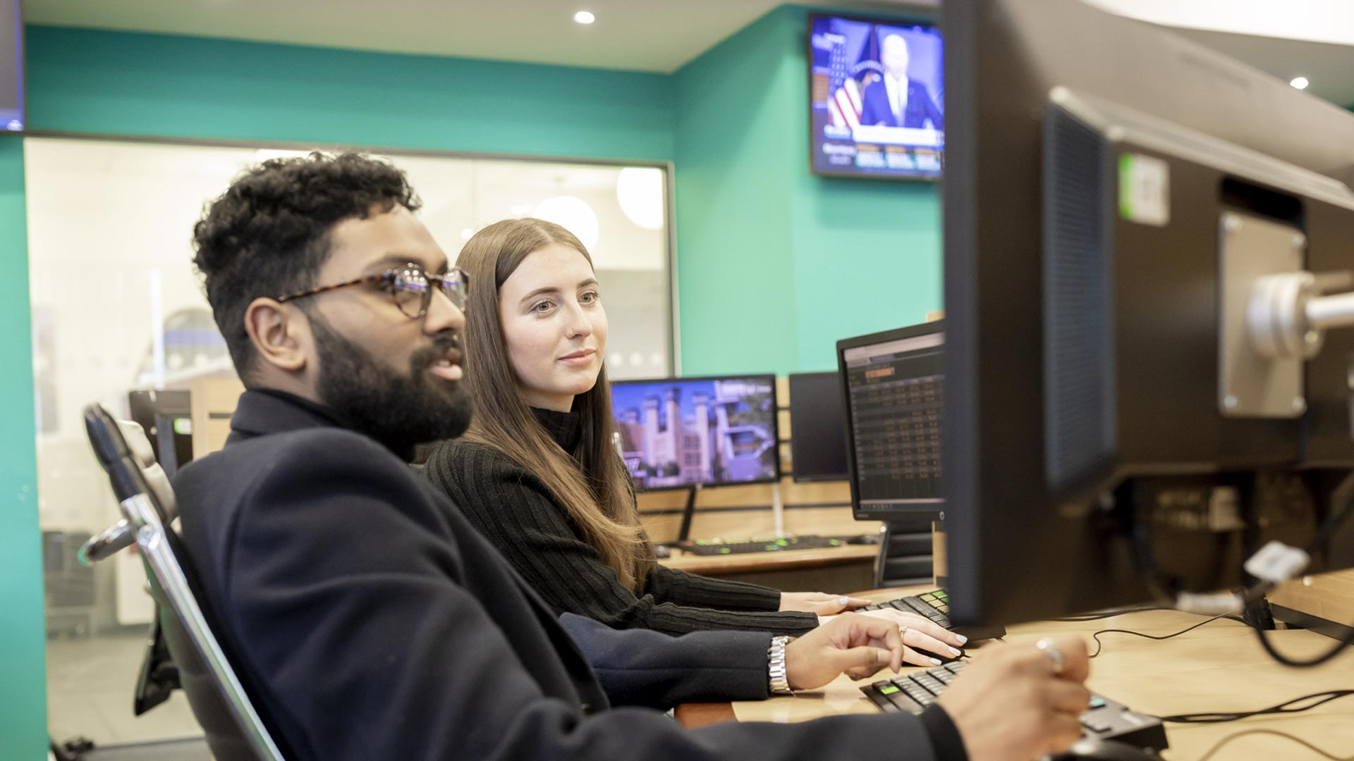 A couple of students sat at a desk working on a computer screen