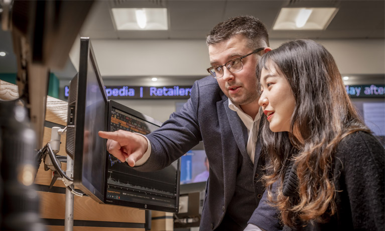 Lecturer speaking to a student pointing to something on a laptop