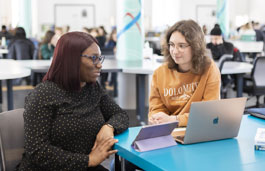 Students working on a laptop in an open plan study area