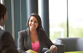 Young professional female chatting to another a male sitting at a table 