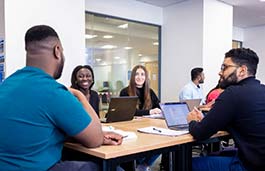 group of students around a table smiling and chatting 