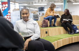 Students talking in an open space with astroturf seating