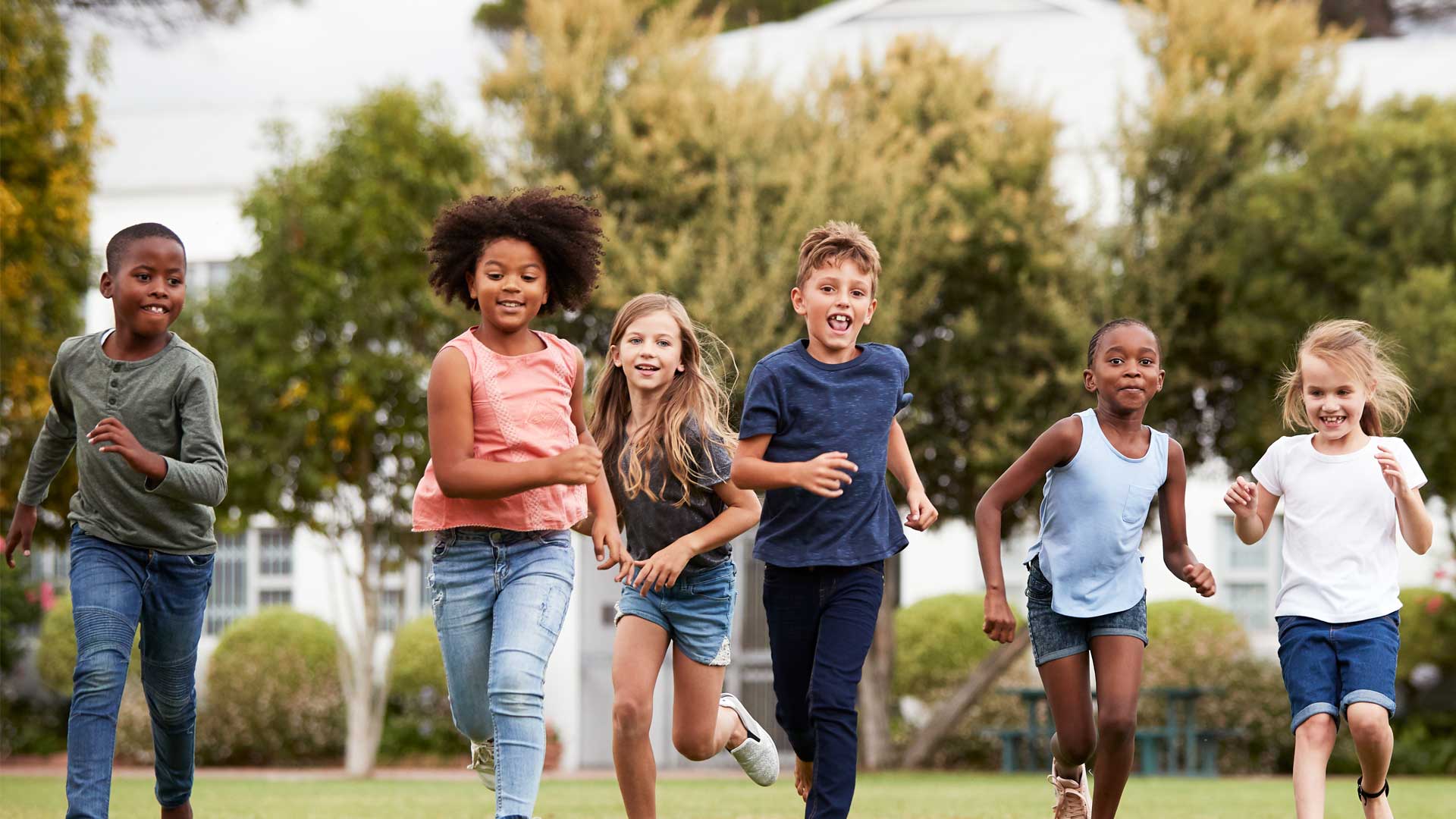 Children laughing as they run across a playing field.