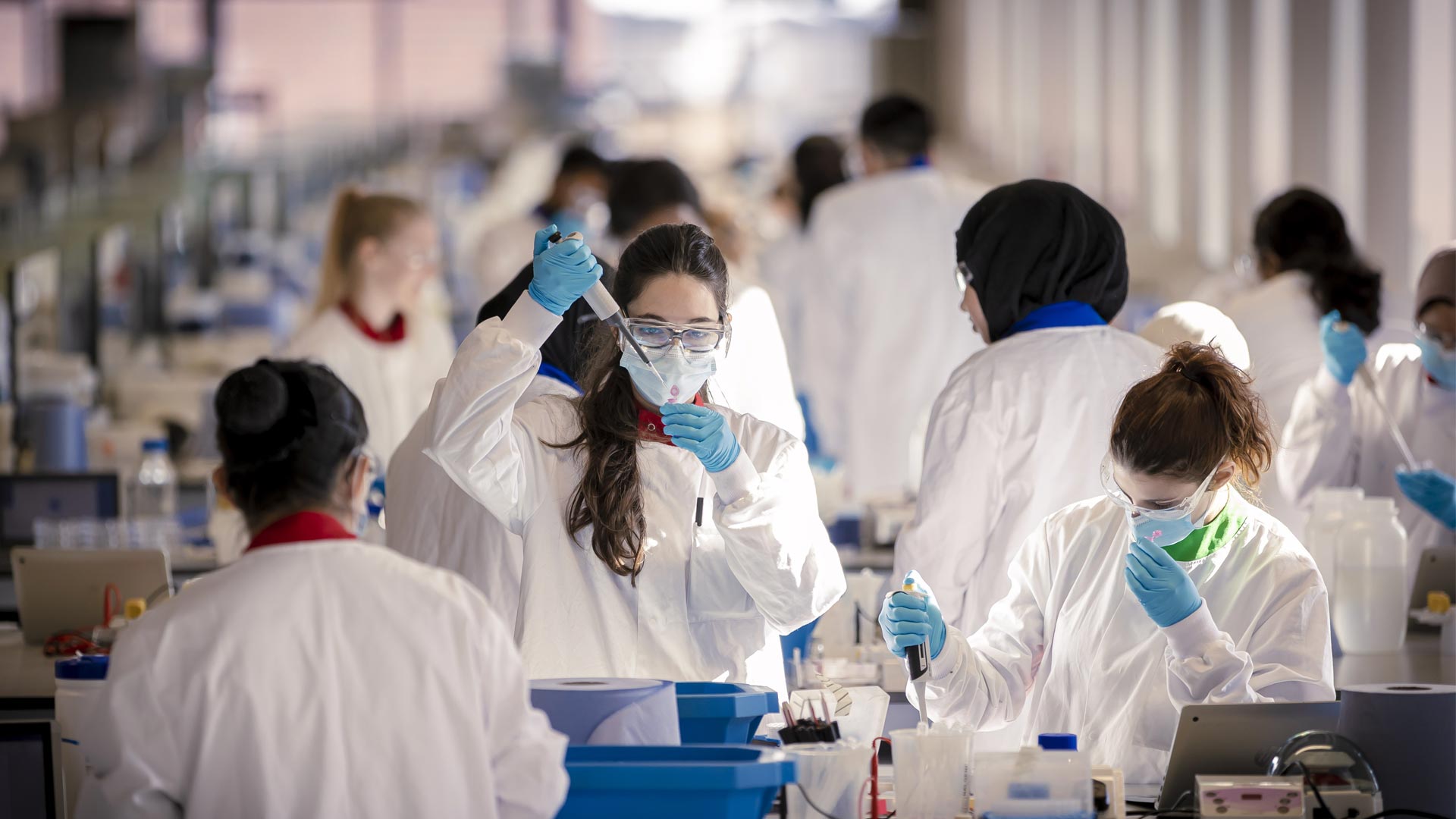 Students wearing white coats and working in the SuperLab