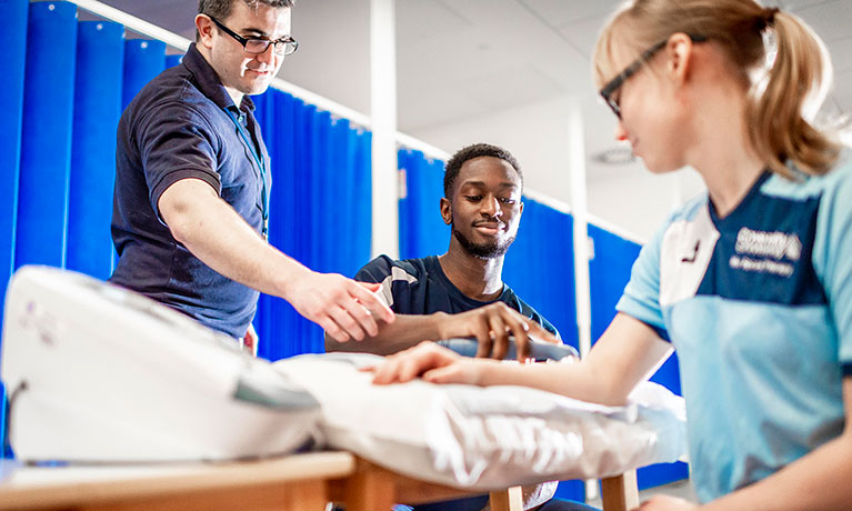 Physiotherapists looking at students arm