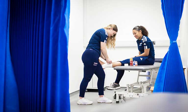 Female student strapping another students ankle