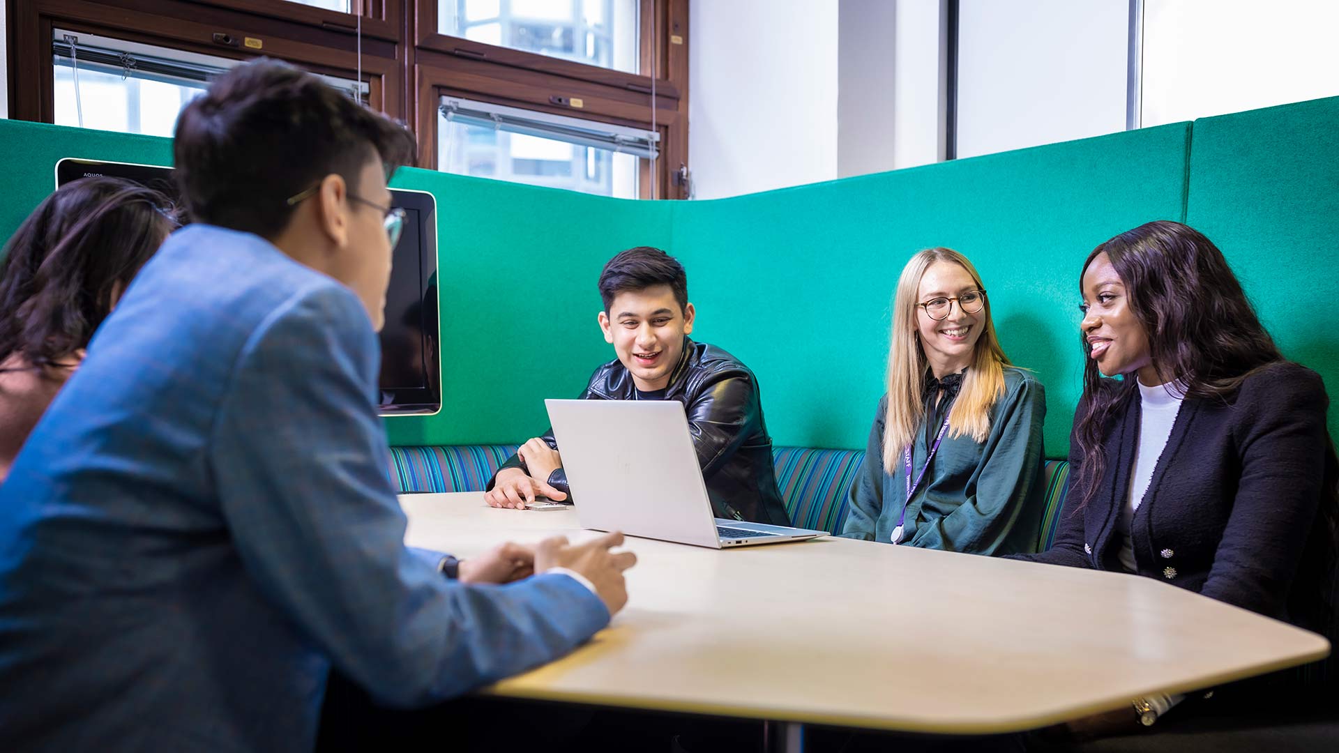 4 professionally dressed young students sitting in a study booth 