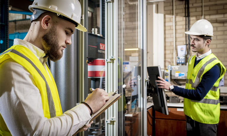 Student in high vis with a clipboard in a construction area