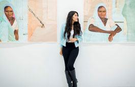 student leaning against a gallery wall with paintings on it