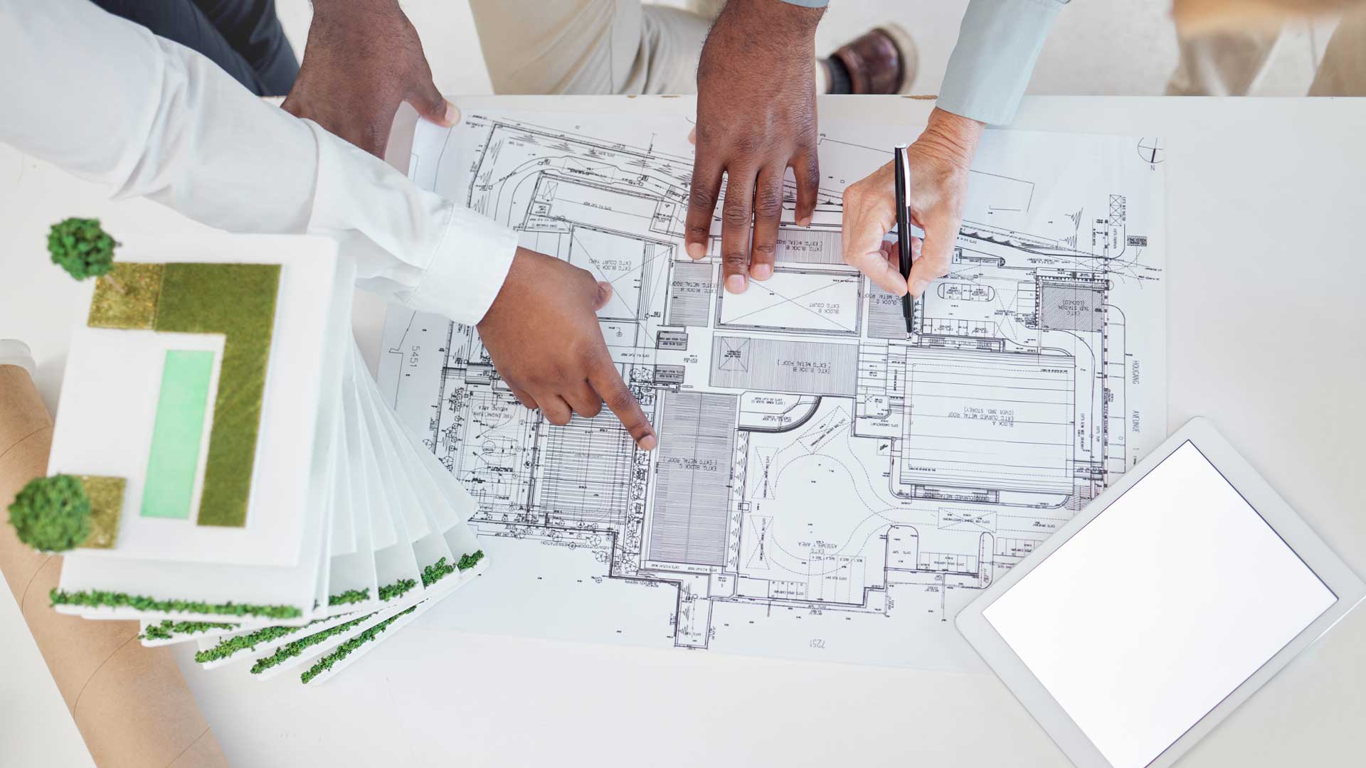 Hands reaching across architectural drawings