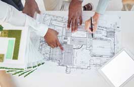 Hands reaching across architectural drawings