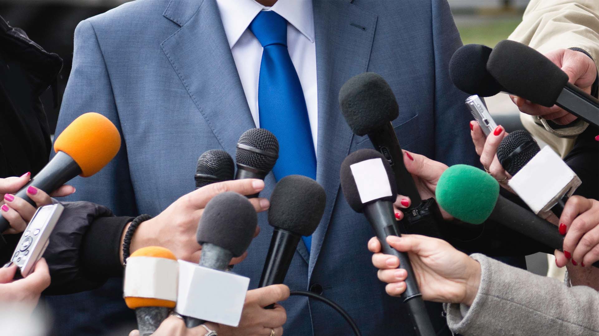 Microphones being pointed at a person in a suit