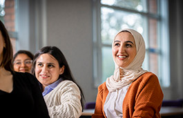 Class full of ladies smiling one of them wearing a white scarf