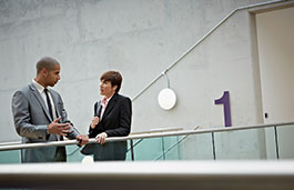 Two professionally dressed people talking in a hallway