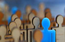 Wooden figures of people, one is bright blue and stands out