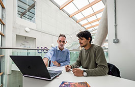 Two males working on a digital product in a grey building