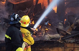 Firefighter with a hose battling a building on fire 