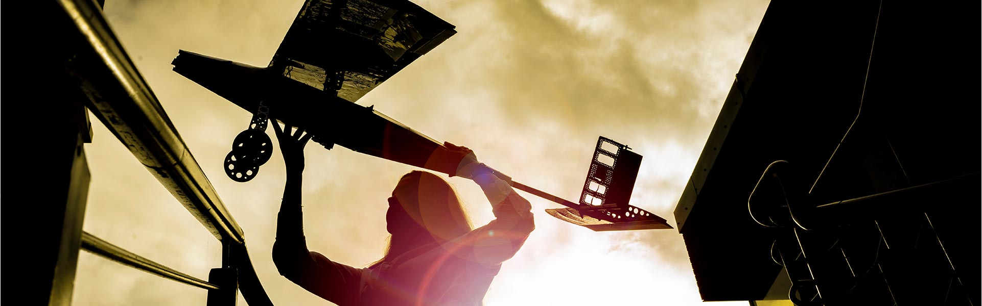 Person holding up a model aeroplane in silhouette