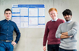 Three students standing in front of a poster