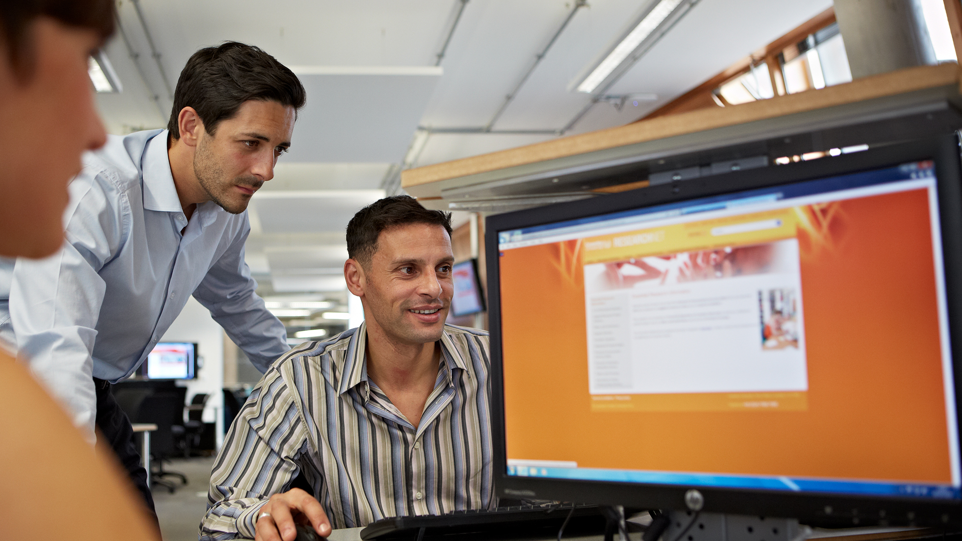 Couple of male students in smart shirts looking at laptop 