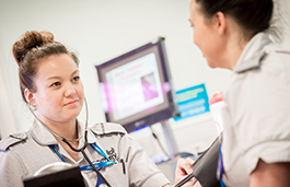 Nurse behind a desk smiling at another staff member