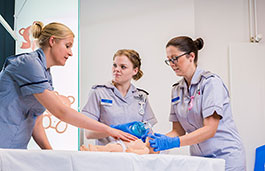 Three nurses in training on a simulation baby. 