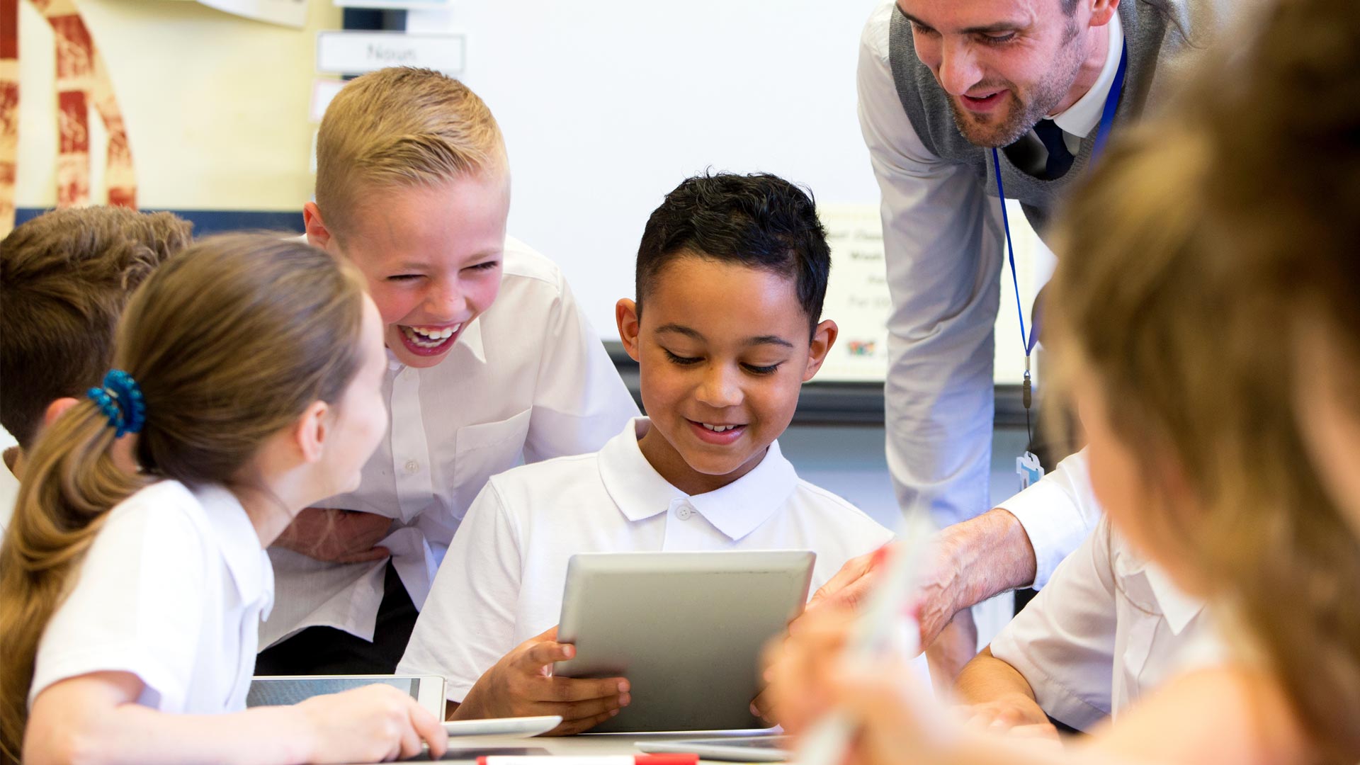 A male teacher working with students using a tablet.