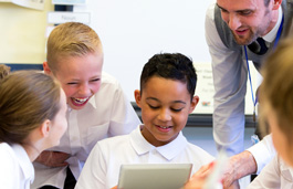 A male teacher working with students using a tablet.